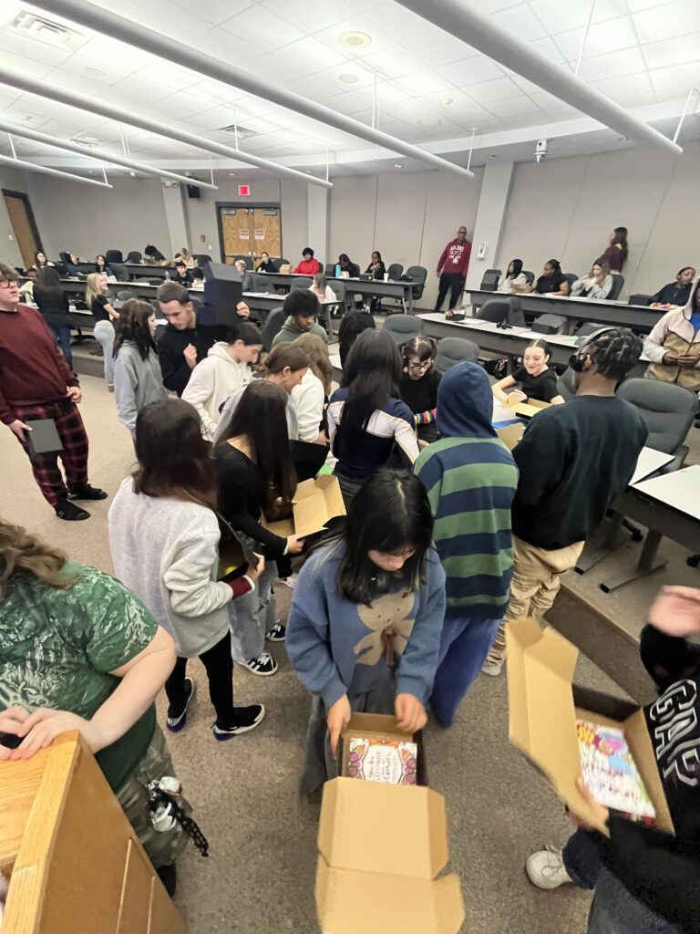 A Classroom Filled With People Gathered Around Boxes